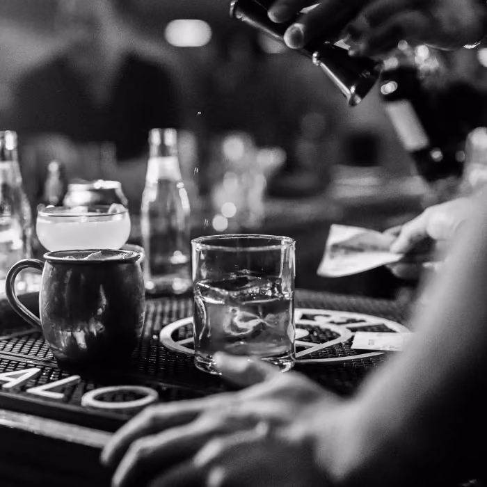 A bartender sets down a mule and a rocks glass on the Rock and Rye bar mat